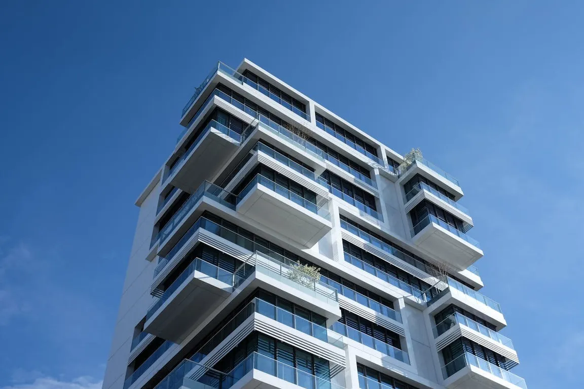 A tall white skyscraper with. bunch of balconies on it