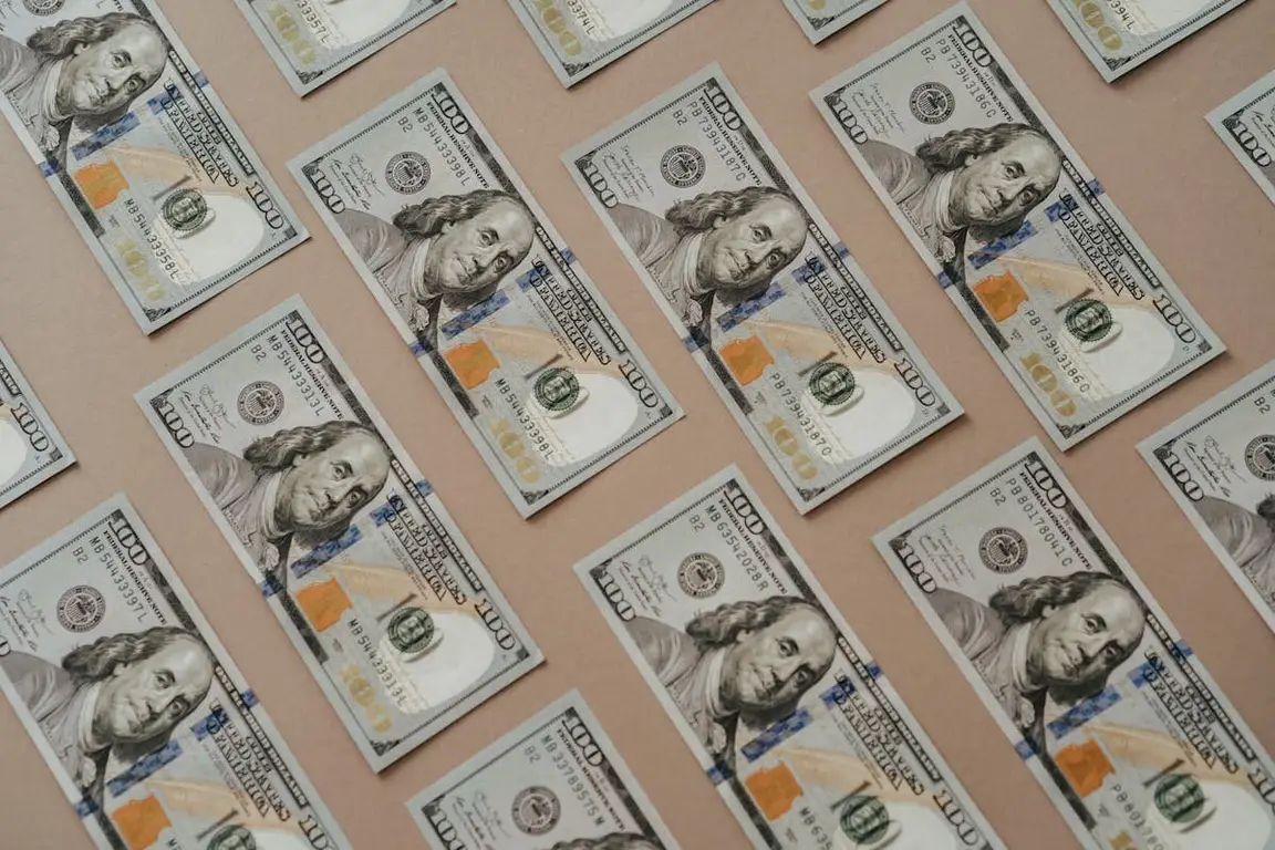 A bunch of 100 dollar bills all laid out evenly on a table
