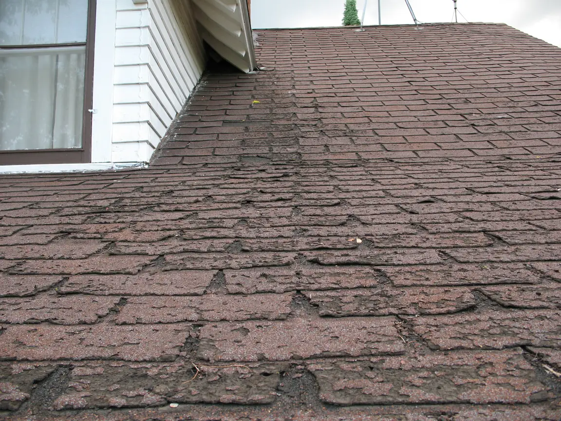 A brown tiled roof displaying signs of problems.