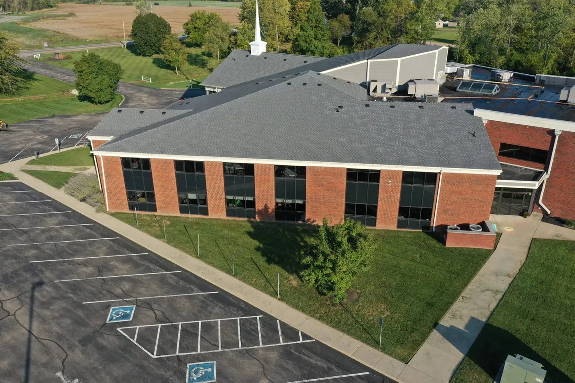 An aerial view of a church building with a commercial roofing.