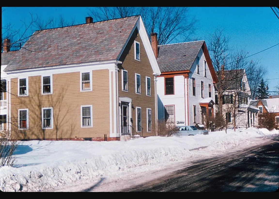 Row of modest New England homes on a snowy residential street in New Hampshire