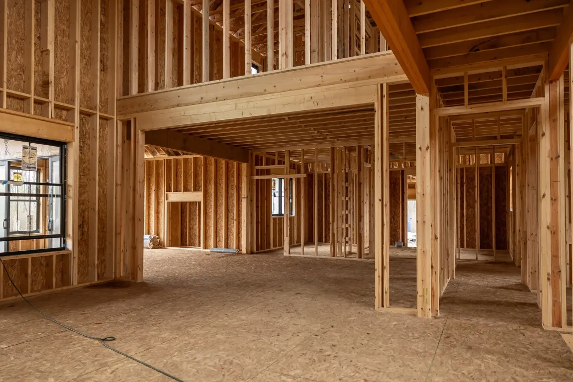 Wood-framed house interior under construction with plywood subfloor and exposed studs