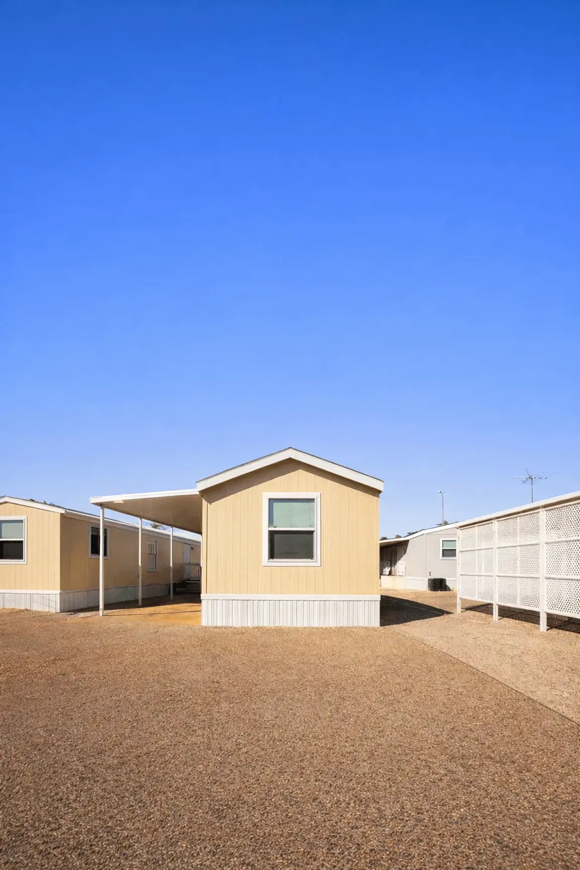 Single-wide mobile home in a Tucson Arizona mobile home park with gravel yard and carport