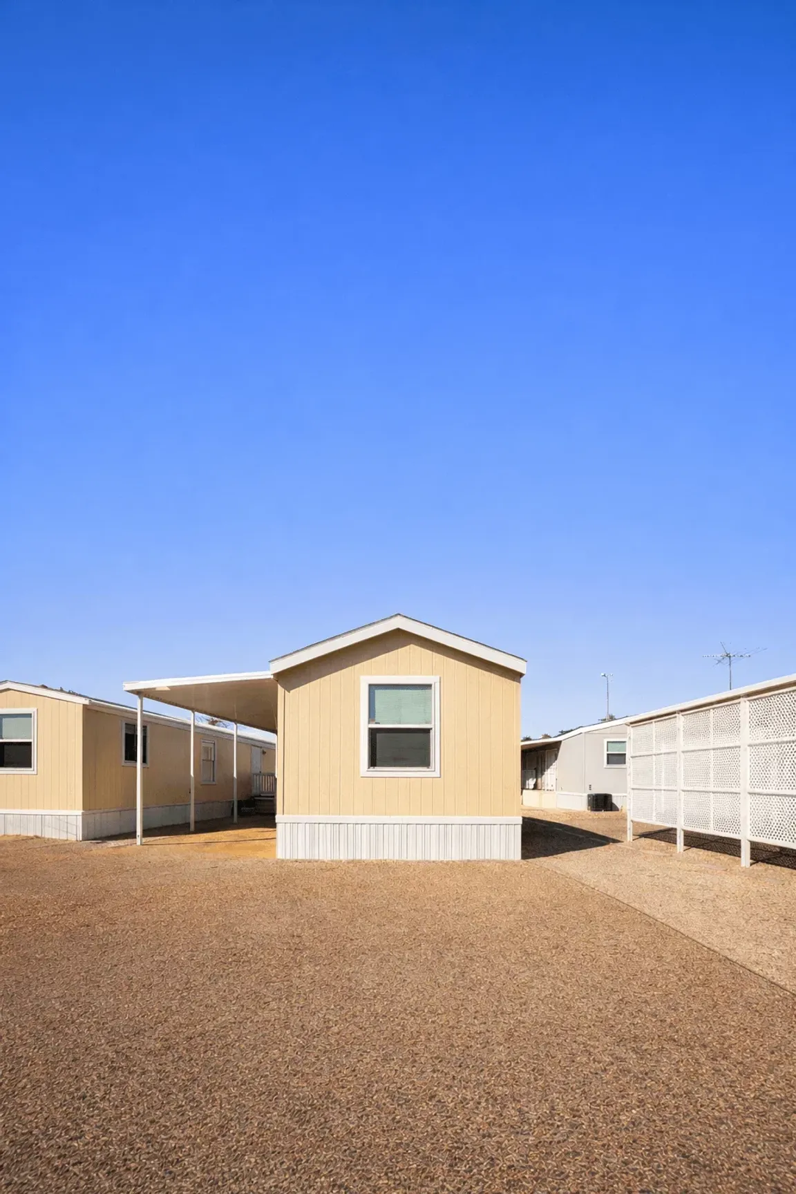 Single-wide mobile home in a Tucson Arizona mobile home park with gravel yard and carport