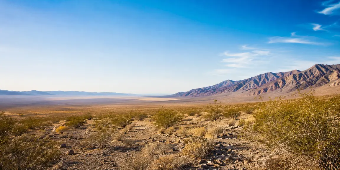 Wide view of the Pahrump Valley in Nevada with desert brush in the foreground and mountains along the horizon