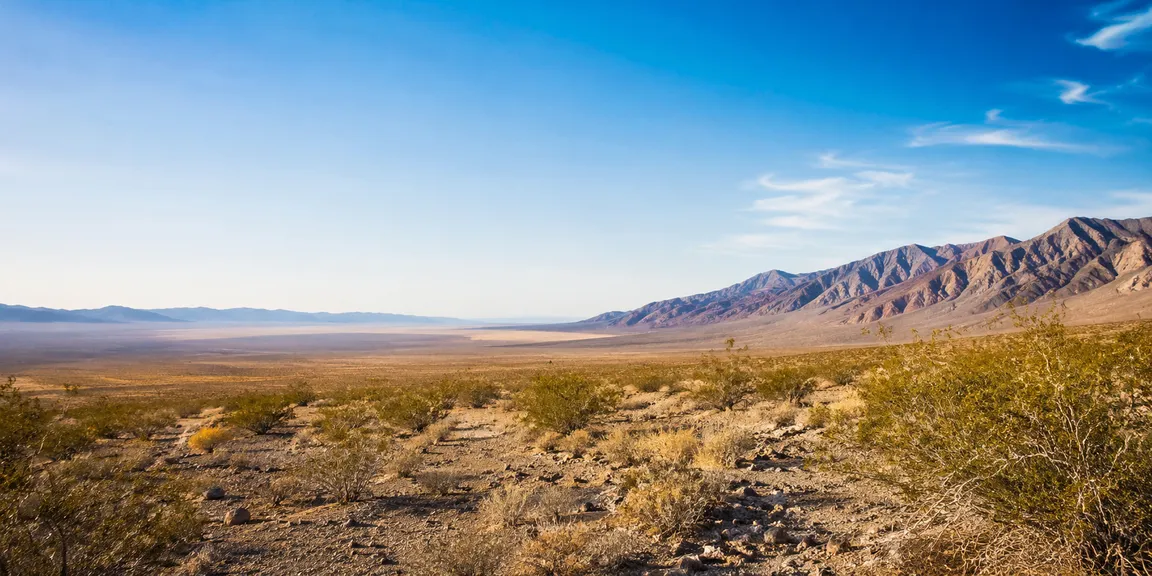 Wide view of the Pahrump Valley in Nevada with desert brush in the foreground and mountains along the horizon