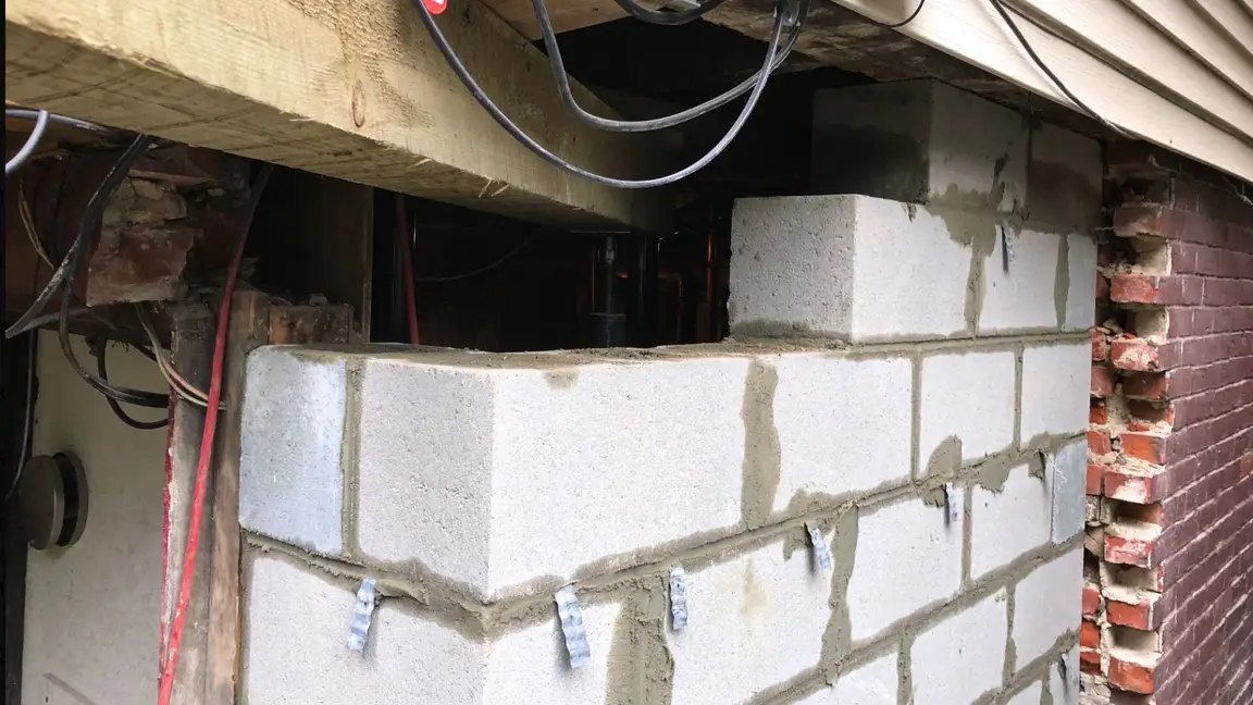 Foundation repair work involving structural support installation and masonry rebuilding