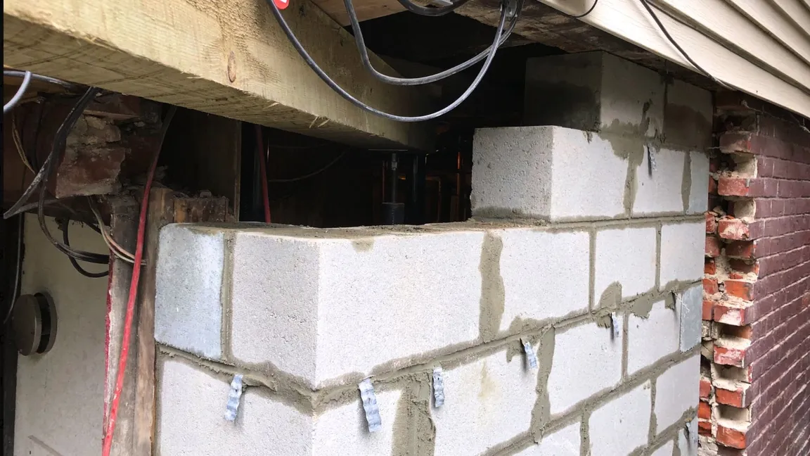 Foundation repair work involving structural support installation and masonry rebuilding