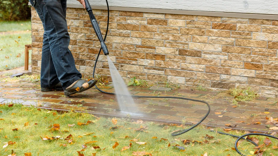 Worker pressure washing walkway