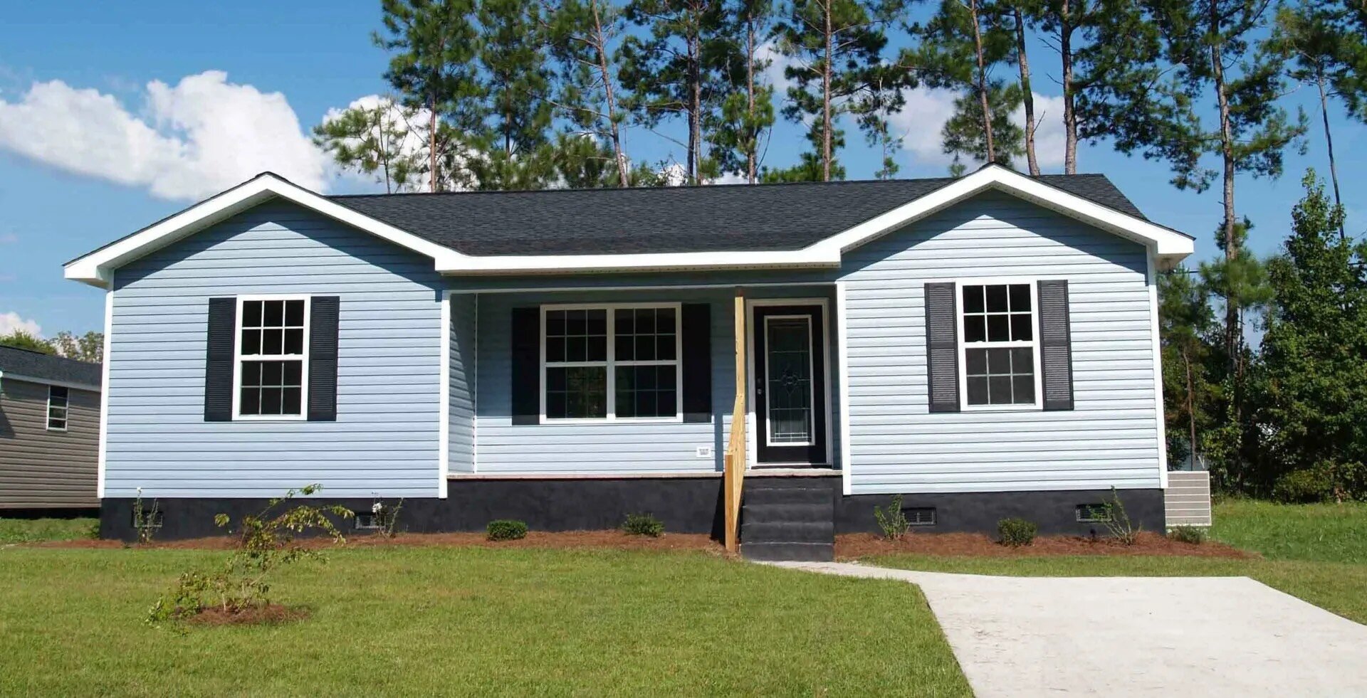 Newly built or remodeled modest single family home with green lawn and driveway