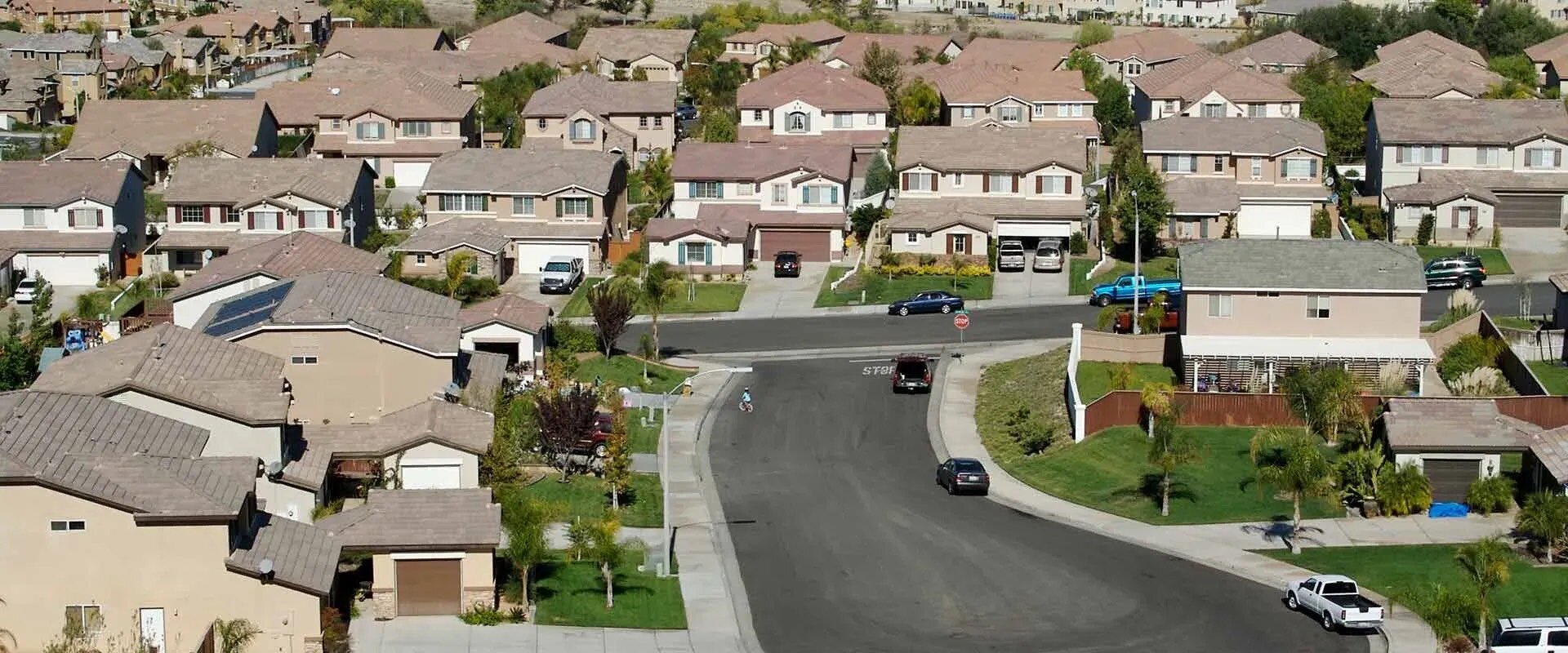 Arial view of suburban neighborhood single family homes built with similar style and construction and green lawns