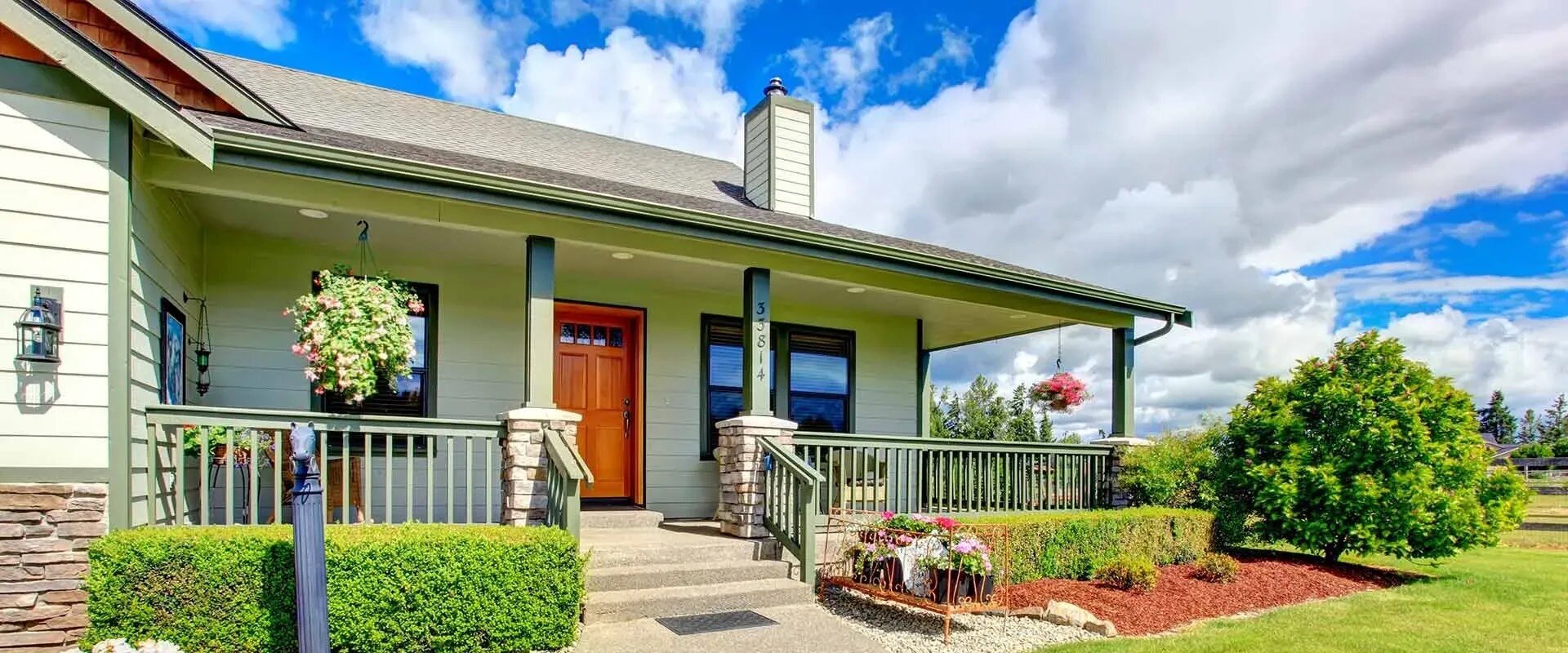 Daytime view of single-family ranch style home with large deck and hanging plants