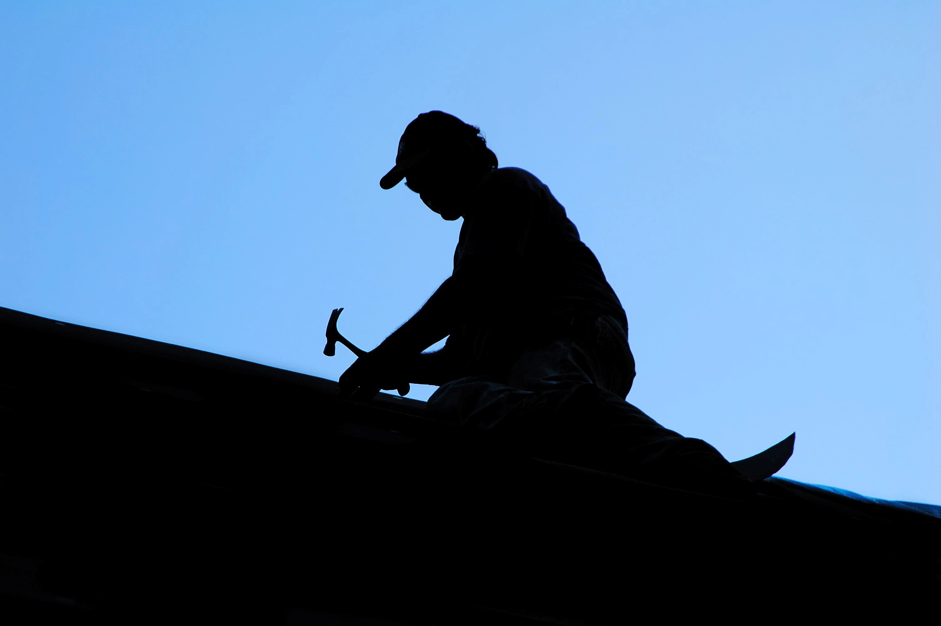 shadow of roofer repairing roof in Roseburg