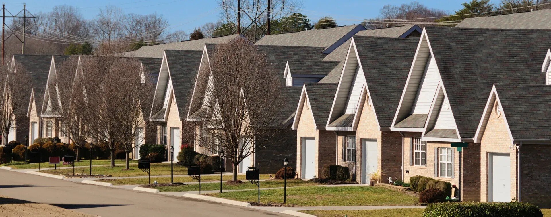 Daytime view of near-identical single family homes in suburban neighborhood
