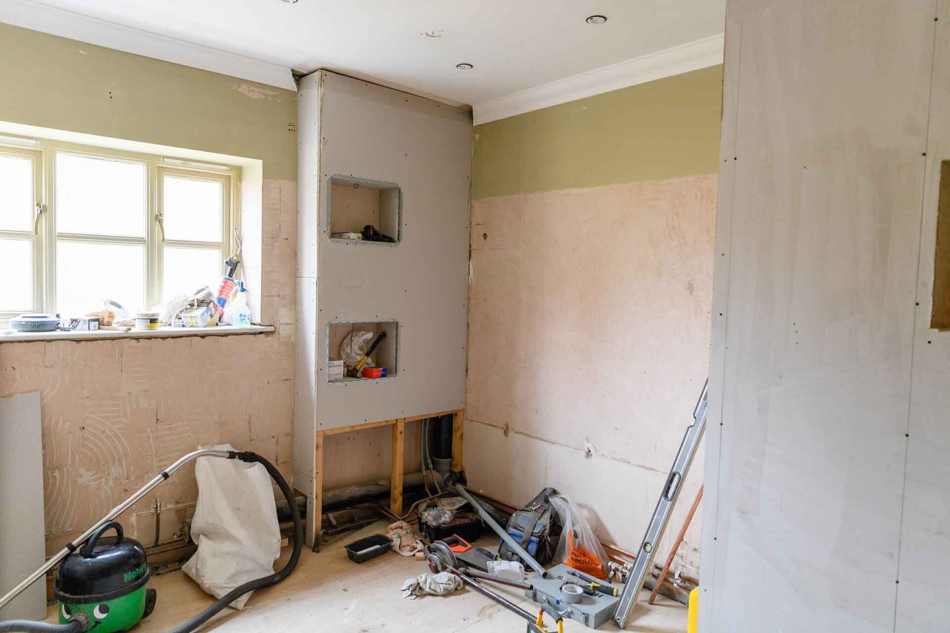 room under major repair and remodeling with unfinished walls, tools and shop vac