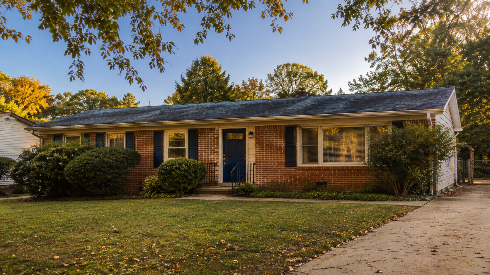 Single-story brick ranch home in a Charlotte, NC neighborhood with mature landscaping and a navy front door.