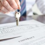 cash buyer holding house keys over a contract
