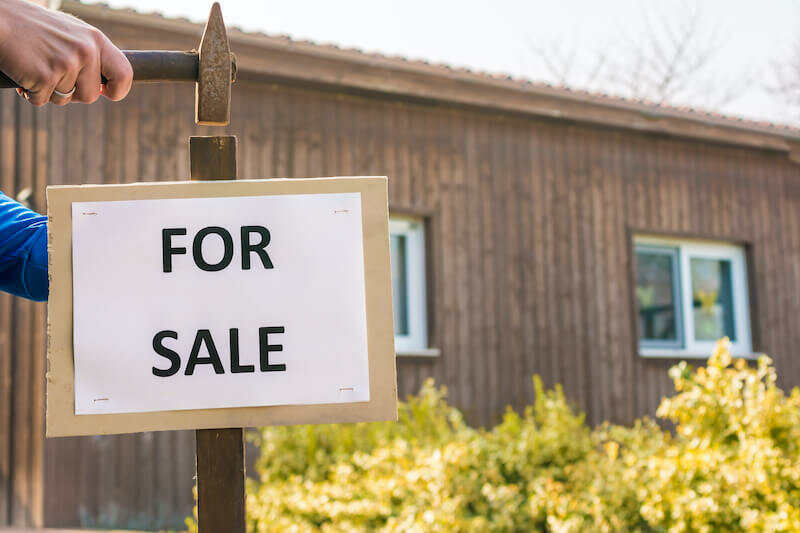 man hammering a for sale sign for a quick house sale