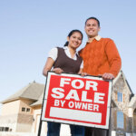 couple with for sale by owner sign selling house on their own