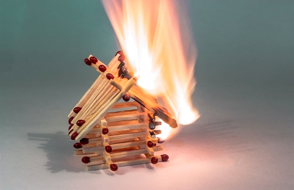 A picture of a house made of matches on fire