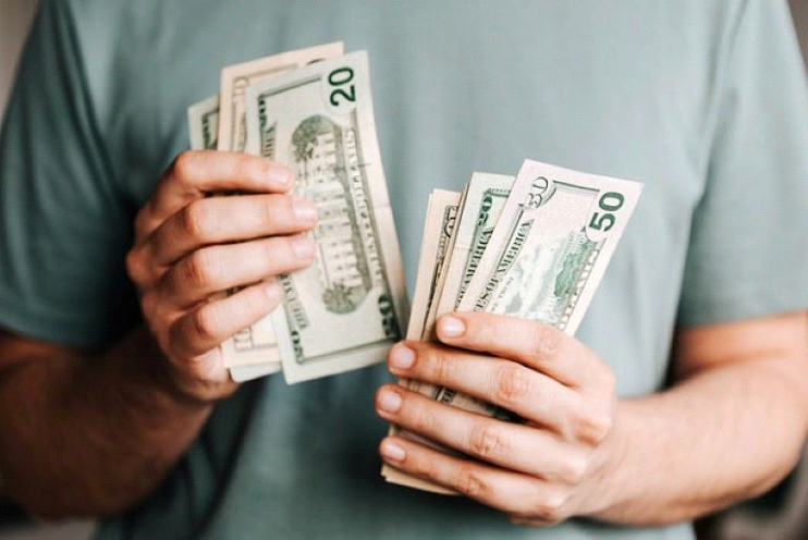 A man is counting banknotes. Sometimes offering your home for cash is the only way of selling a house with fire damage in Wilson County.
