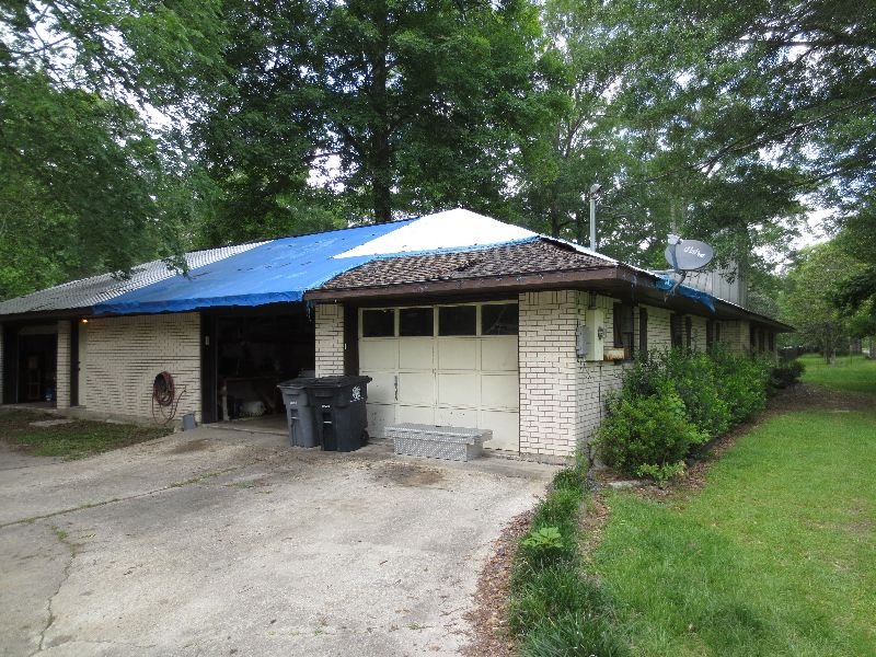 A charming Baton Rouge bungalow-style home with a large front porch and classic Southern architecture, surrounded by greenery.