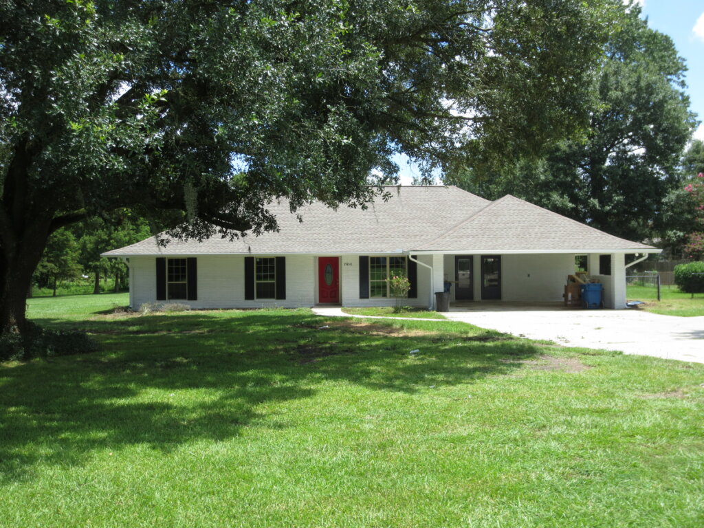 A cozy, single-story brick house in Baton Rouge with a well-maintained front yard and a tree-lined street, perfect for a family home.