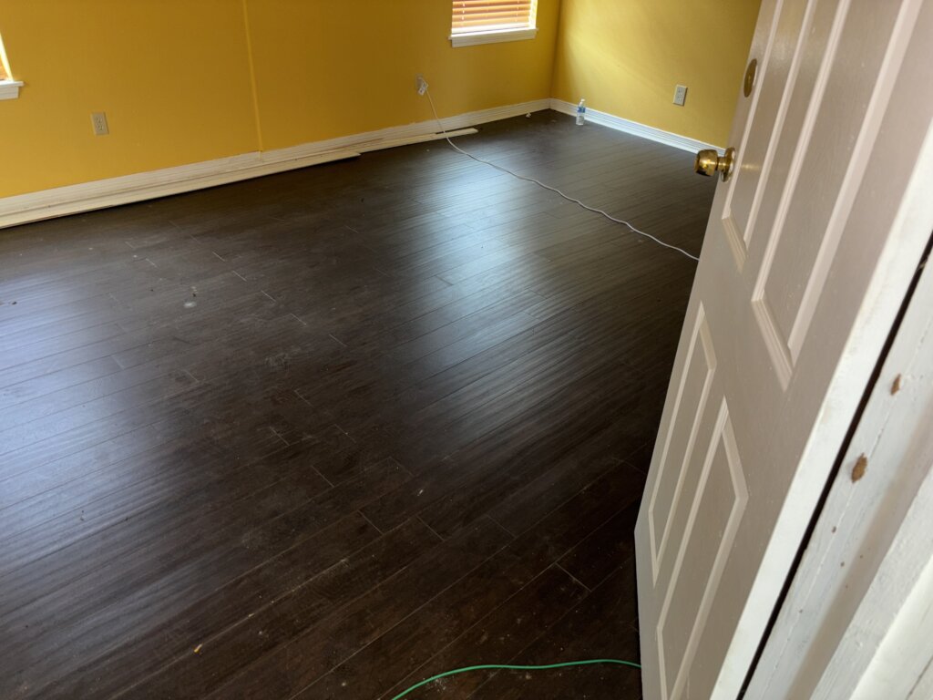 Interior flooring with visible waves and dips, showing signs of termite damage and subfloor instability
