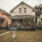 A Baton Rouge single-family home with a “For Sale” sign in the yard under a cloudy sky, representing a slow housing market and homes taking longer to sell.