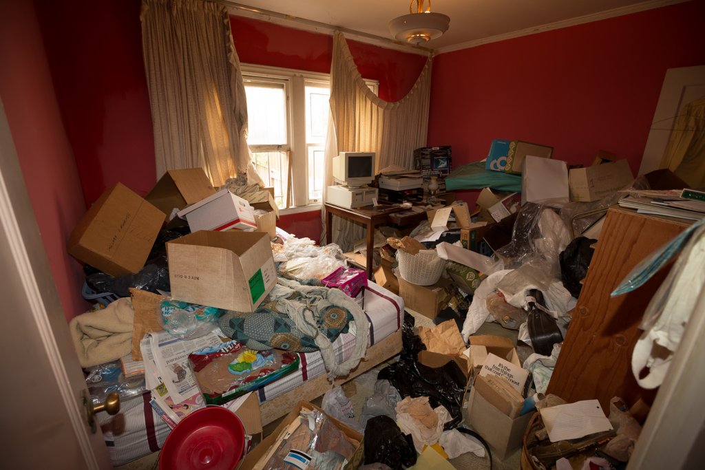 A living room full of boxes and papers in a hoarder house.