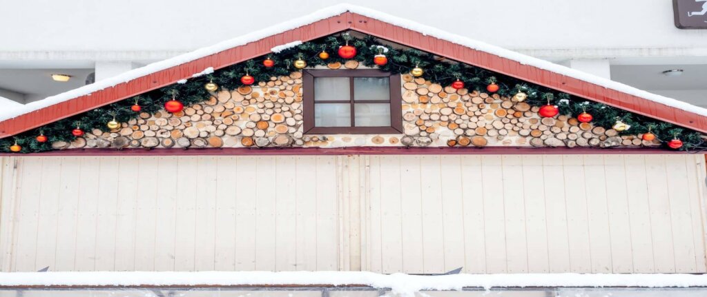 front of house in snow with holiday decorations