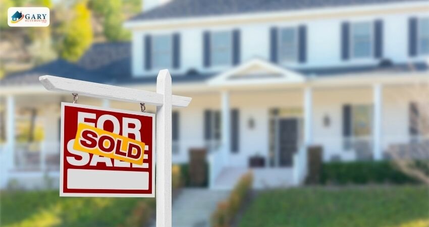 A "For Sale" sign in front of a house with "Sold" across it