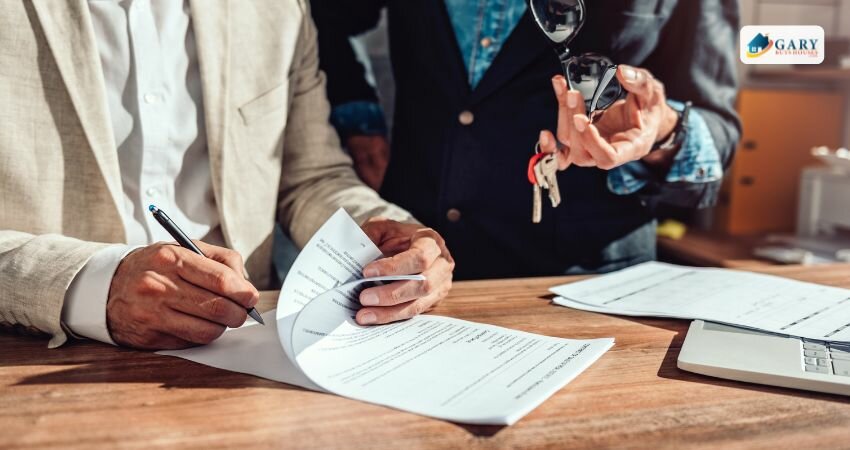 A man signing papers with a companion holding keys