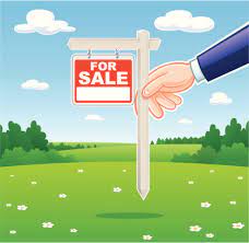 a person putting a for sale sign in the grass in reference to preparing the land for sale