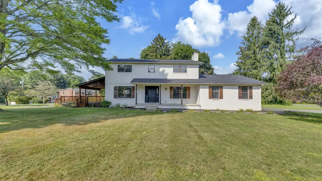Front exterior of the same Millstone Drive house after renovation, with the covered porch, dark front door and landscaped front lawn