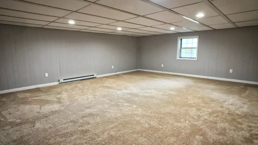 The same room after renovation, with gray walls, light carpet and recessed lights