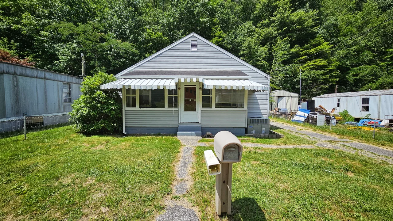Same Georges Creek house in June 2024 with gray siding and an enclosed front porch