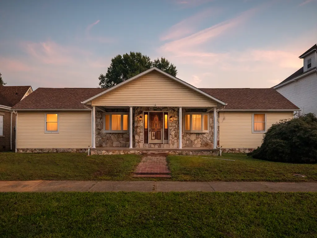 The same Collis Avenue house after renovation, photographed at dusk with a clear front walk and illuminated porch