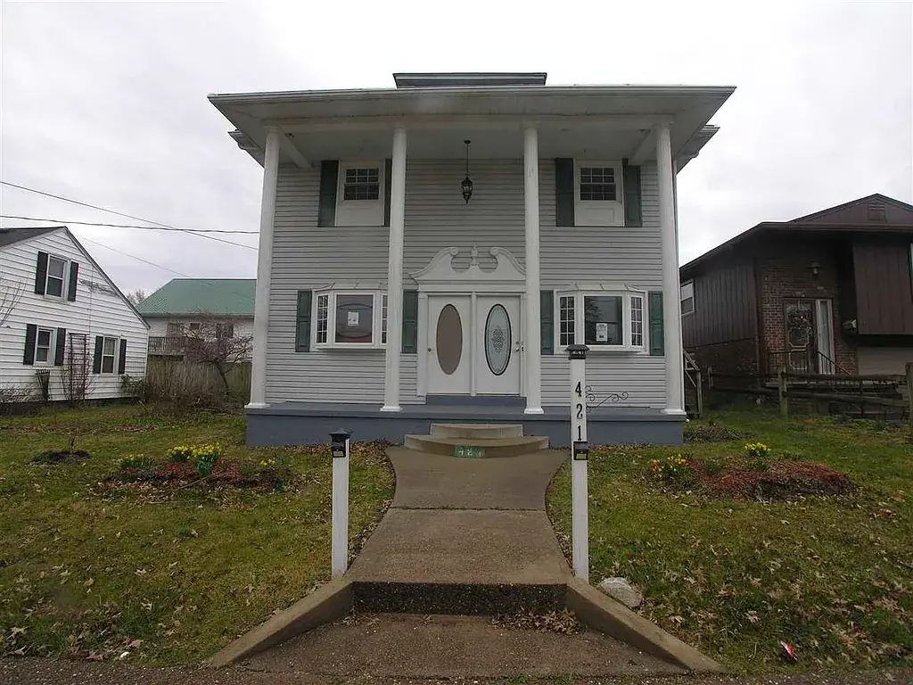 Front of the Dudding house in Hurricane before renovation, with tall porch columns and paired oval-glass entry doors