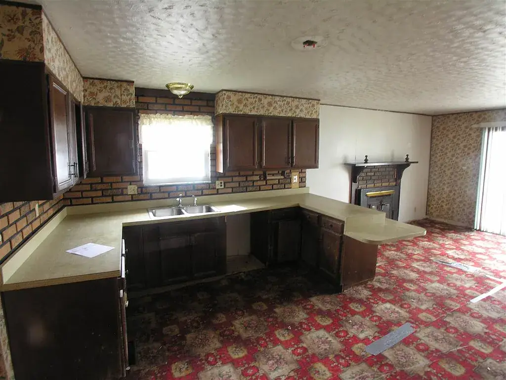 Dudding house kitchen before renovation, with dark cabinets, pale counters and red patterned flooring