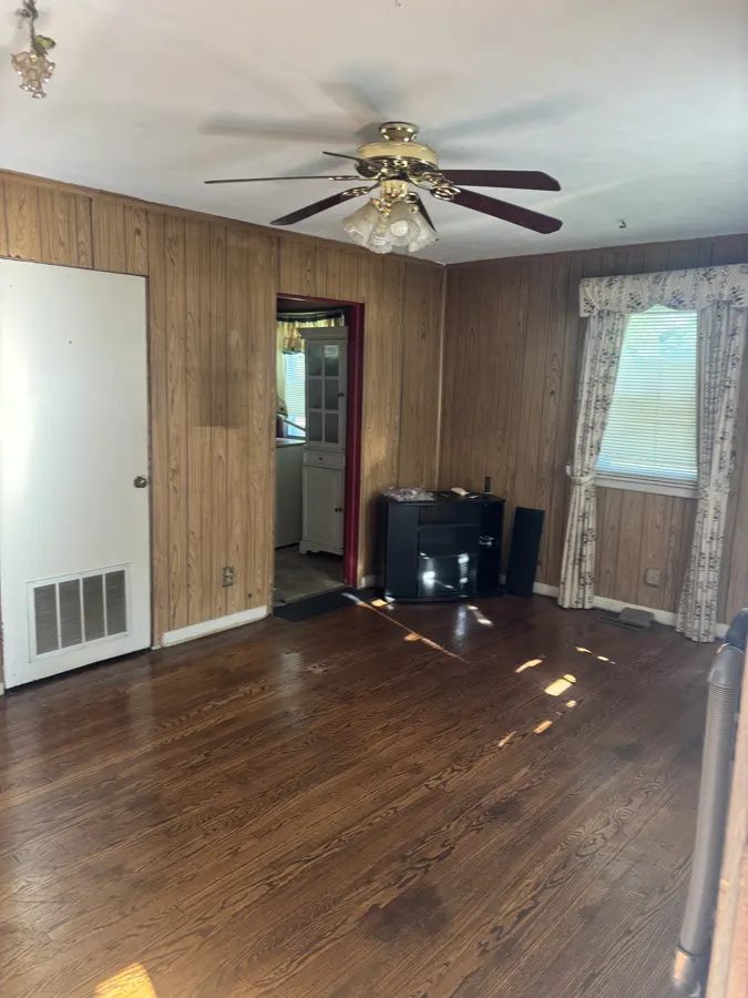 King Street living room before project work, with wood paneling and hardwood flooring