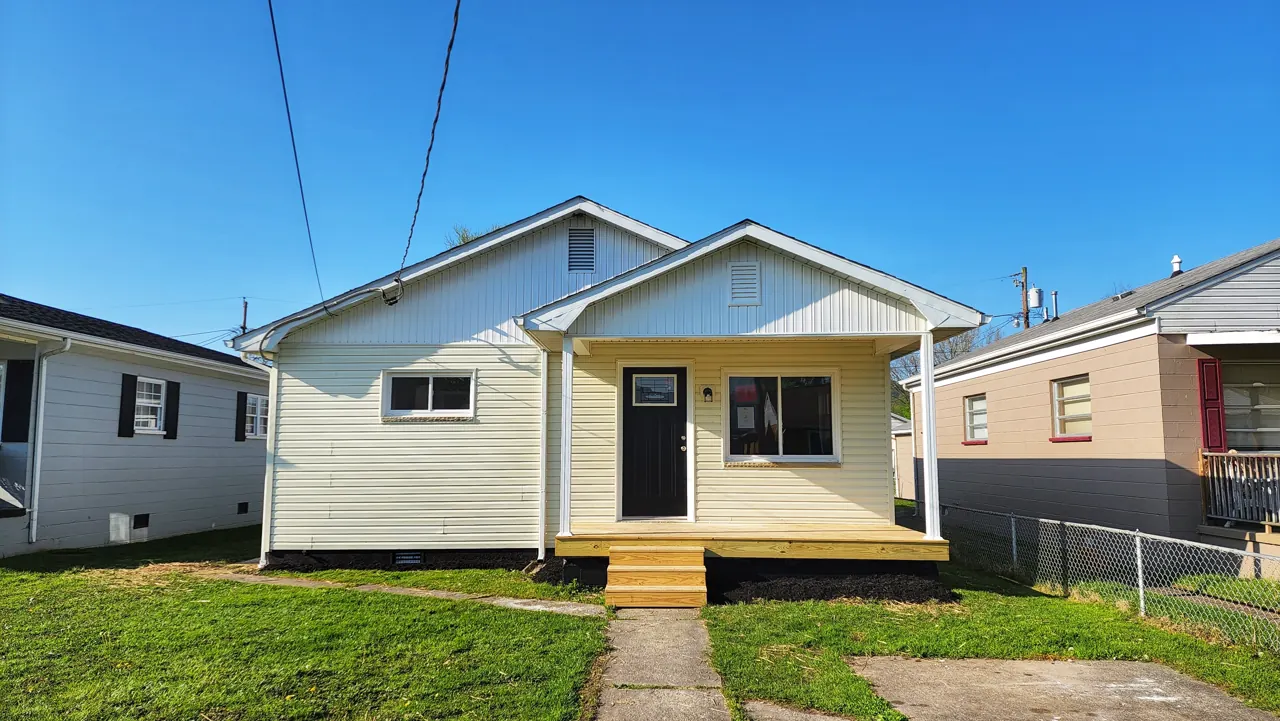 Same McKinley Avenue house after renovation with light siding, dark door and wooden front steps
