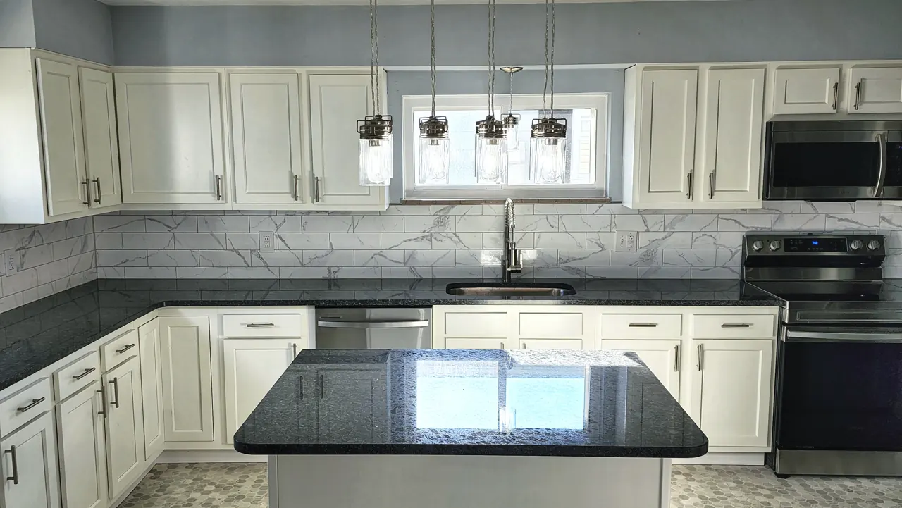 Same McKinley Avenue kitchen with light cabinets, dark counters, appliances and pendant lighting