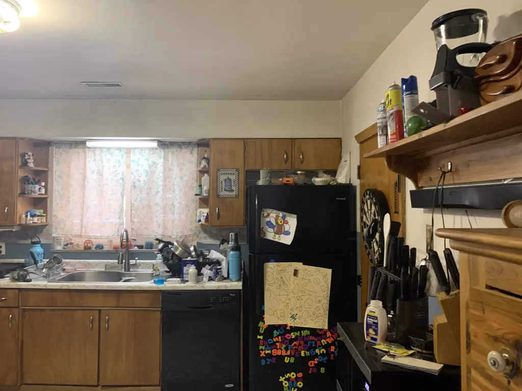 Hallison Circle kitchen before renovation, with wood cabinets, pale counters and black appliances