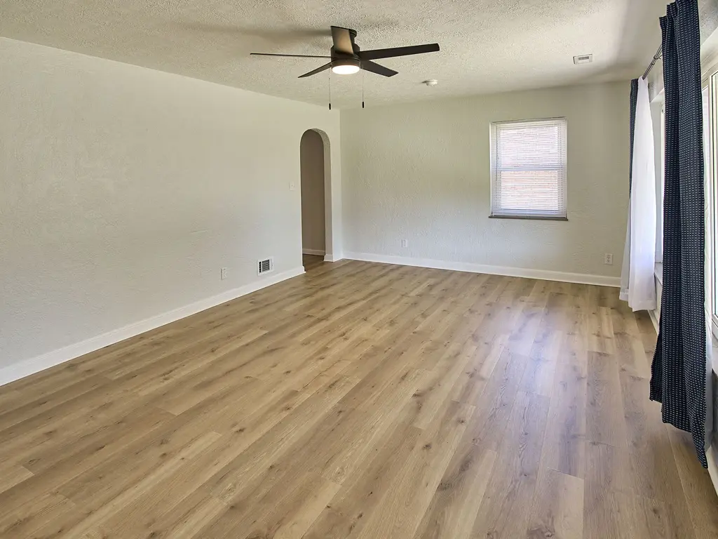 Renovated living room at the same Hallison Circle house, with light wood-look flooring and a ceiling fan