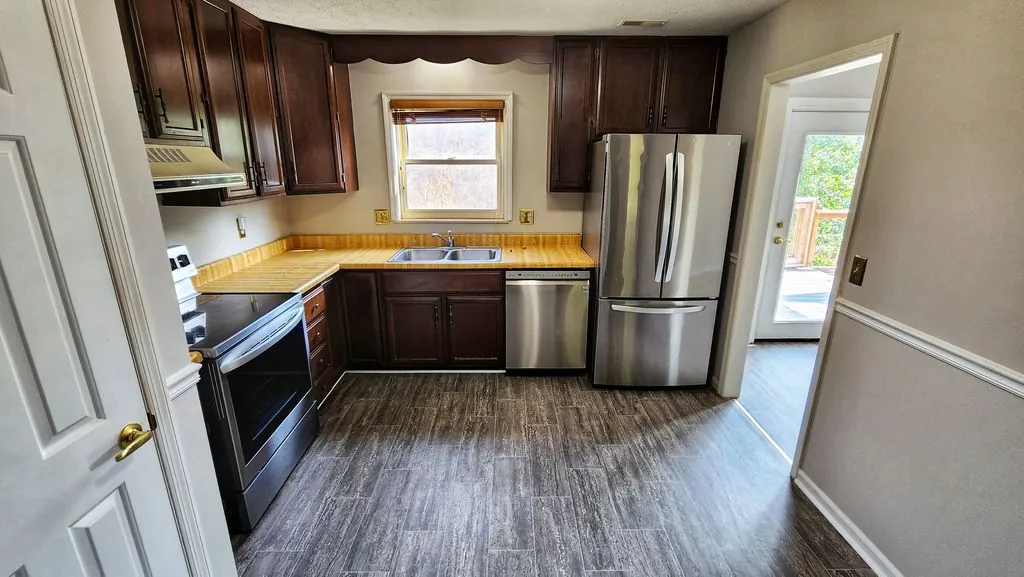 Updated kitchen with dark wood cabinets, stainless-steel appliances, and gray plank flooring at a Nitro renovation project