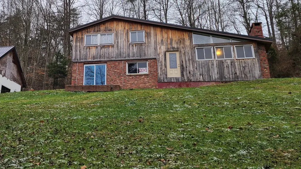 Exterior of the Pawnee Drive house in Sissonville before work, showing weathered wood siding and brick lower walls