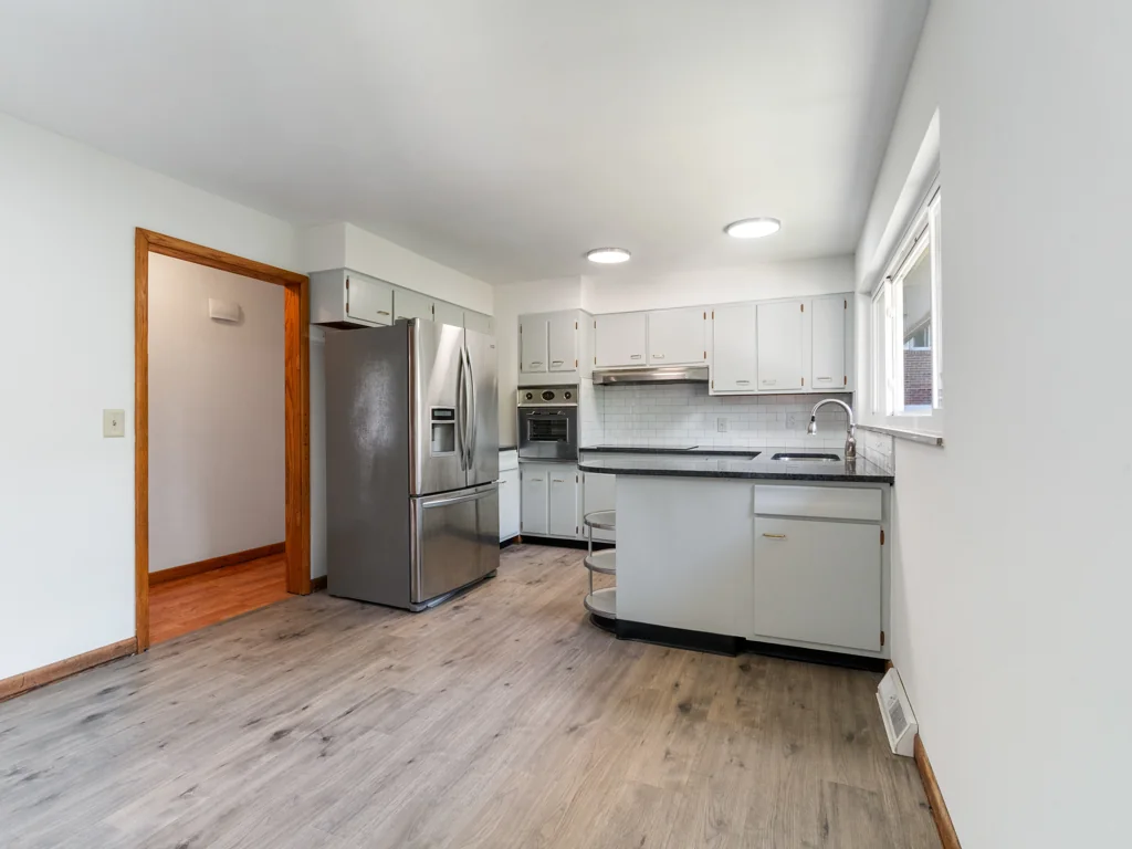 The same kitchen at 1212 Crown Drive in South Charleston, WV, after renovation, with white cabinets, dark counters, updated flooring and ceiling lights
