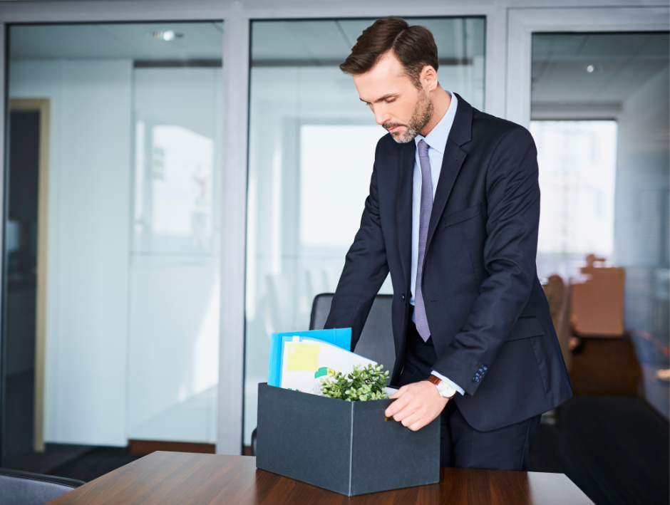 Person packing up office because of a job transfer, representing an emergency need to sell a house quickly for cash in California to Homesmith Group. Call 855-HOMESMITH