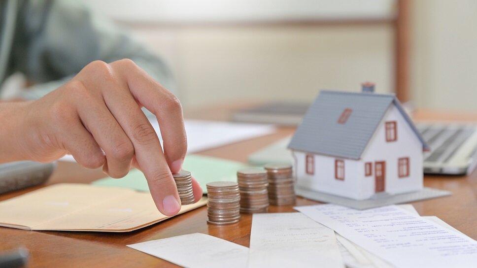 Close - up shot of Model house and hand are arranged coins, House buying concepts.